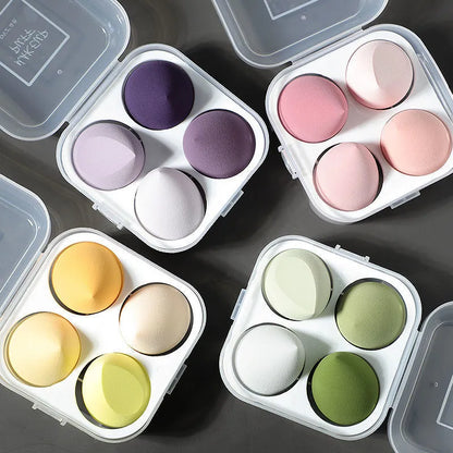 Set of colorful makeup sponges in a compact case on a dark surface.